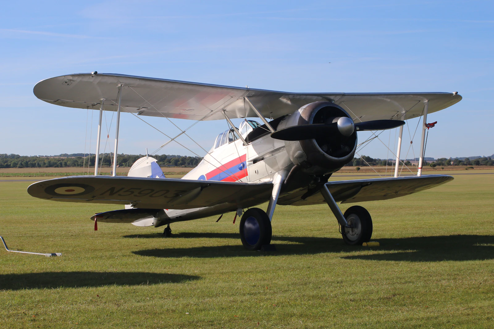 A classic biplane parked on a grassy airfield.