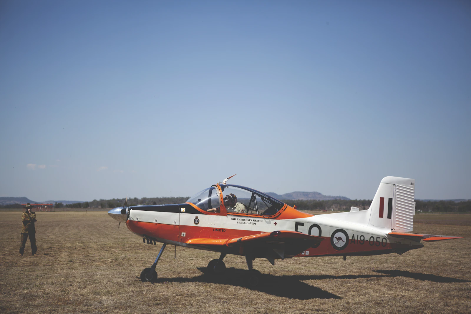 A small airplane resting on a dry grass field.