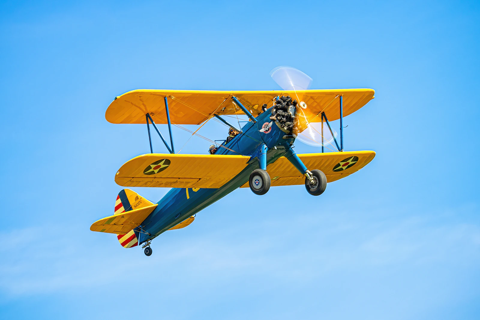 A vintage biplane soaring through a bright blue sky.